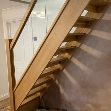 Staircase replacement image after fire damage. Glass and oak staircase with open risers